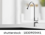 Stylish metallic crane at the kitchen.Shiny faucet at the kitchen.Metal crane in close-up photo.Modern furniture. Silver sink as kitchen equipment. Macro photo with high quality. Metallic faucet.