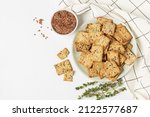 Square diet cookies with thyme, flax seeds and spices  in a light plate on white background. Crunchy herbal crackers top view with copy space