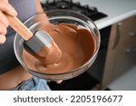 Small photo of The process of tempering chocolate and making chocolates. Pastry chef using spatula tempering molten chocolate.