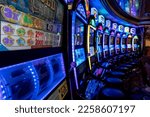 Small photo of Las Vegas -2023: Casino slot machines. Dark background, neon lights, intentional background blur. One armed bandit, fruit machine, coin, gaming, pokie, slots, puggy, gambling.