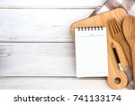  Notepad on chopping board with wooden fork and spoon  on white table , recipes food or diet plan for healthy habits shot note background concept