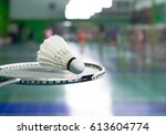 racket and white shuttlecock over blurred of badminton court with players playing badminton