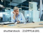 sad gray-haired architect man working in modern office at computer, businessman thinking about failures