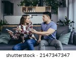 Small photo of Married couple, man and woman, sitting on the couch at home and arguing over the phone, jealousy