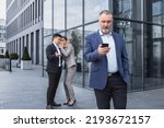 Small photo of Two colleagues are gossiping at background behind the boss. workmate about bullying problem at work place in office in the break outside Male Coworkers employees man and woman Whispering Behind Back