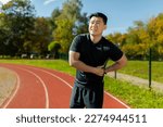 Small photo of Asian sportsman has severe pain in back and abdominal muscles, man peed training in stadium on sunny day massaging side of back, athlete on jogging pulled muscle.