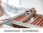 Small photo of The clerk is leafing through stored folders, looking for a file or document. Concept of data storage, filing cabinet and business administration.