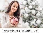 Woman saving money for Christmas while putting a two euro coin into a piggy bank.