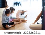 Small photo of Female instructor in a gymnastics class teaching stretching to a toddler