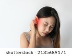 Small photo of Asian woman with sore ear suffering from otitis with red accent. Stressed frowning young girl from strong ear pain feeling painful discomfort isolated on white studio background. Copy space, closeup