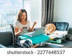 Small photo of Happy Asian woman using credit card booking flight tickets and hotel at home. Planning a trip and online booking, cashless society, technology and lifestyle, Summer vacation concept. Free space