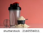 Shaker and protein powder on pink background. Sports nutrition concept.