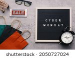 Creative flat lay promotion composition Cyber Monday sale text on letter board with alarm clock goodie bag and gadget