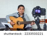 Child guitarist influencer making video online streaming or video lessons and tutorials for internet vlog website classes.