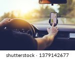 Driver using GPS navigation in mobile phone while driving car at sunset