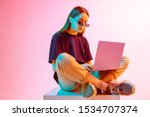 Modern Girl with laptop, tablet computer. Free creativity. Young blogger makes a Home office. Colored Neon light and background.