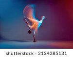 Cool young breakdancer dancing hip-hop in neon studio light, standing on hand. Dance school advertising. Long exposure