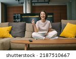 Small photo of Laughing girl watching stand up comedy, comedian show, sitting with popcorn before television on sofa, rests at home