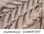 Small photo of Footprint of wheel tread on the ground road. The trail from the tread of trucks wheels. Car tire tread imprint on sand, background, texture. Footprints rubber tyres from automobile. Close-up