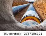 Small photo of Insulated pipe. Large metal pipes with a plastic sheath laid in a trench. Modern pipeline for supplying hot water and heating to a residential area