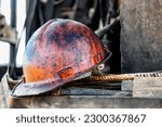 Small photo of The protective helmet of an oil worker is stained with oil and fuel oil. Extraction of oil and coal. Hard work in mining. Dirty brutal helmet of a miner