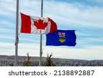 Small photo of A Canadian flag and a province of Alberta Flag waving with the wind half-mast or half-staff refers to a flag flying below the summit a symbol of respect, mourning, distress, or in some cases, a salute
