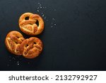 Small photo of Bavarian pretzels and glass of lager beer. Oktoberfest food menu, traditional salted pretzels on black background. Top view with space for text. Oktoberfest theme
