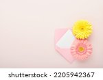 8 March. International Womens Day. Two gerberas pink and yellow, pink envelope on pink background. Copy space. Mock up. Flower concept. Design pattern. 8 march holiday.