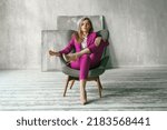Young businesswoman. Beautiful woman director, head, general manager, ceo in astylish bright business pink, fuchsia color suit at photoshoot in armchair. Business purposeful ambitious girl careerist.