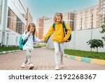 Small photo of Back to elementary,primary school.Little girls,sisters with big backpack go in hurry,late to first grade alone in autumn morning.Education,future of children.Happy,unhappy pupils kids walk themselves.