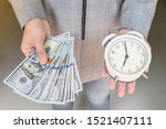 Asian business woman hold alarm clock and money in hand.  Business financial concept. Time is valuable as money. 