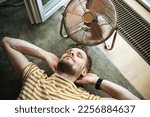 Small photo of During a summer heat wave, a man finds respite by lying on the floor with the help of an electric fan. A man beats the summer heat wave by finding relief with an electric fan
