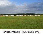 Small photo of MAIDENHEAD, ENGLAND - 09 07 2022: A long row of Piper Archer airplanes and a single Beechcraft Bonanza to the right on the grass at White Waltham Airfield