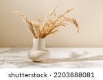 Beige ceramic vase with dry pampas grass and shadows on the table, scandinavian interior decoration, aesthetic style, copy space