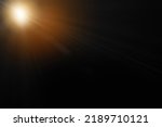 Abstract sun flare over black background. lens flare effect Golden sun light.
