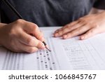 Students hand holding pencil writing selected choice on answer sheets and Mathematics question sheets. students testing doing examination. school exam 