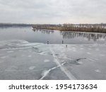 Small photo of Fishermen on thin ice. Frosty drawing on ice. Aerial drone view. Winter cloudy morning.