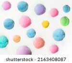 random arrangement of small fluffy pastel colored pom pom balls on a white background