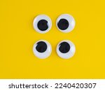 two pairs of  googly eyes funny Isolated on bright yellow background copy space logo