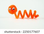 Small photo of googly eyed pom pom pipe cleaner wriggly worm funny character childs toy hand made isolated on a white background