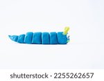Small photo of plasticine play dough wriggly worm in blue and yellow isolated on a white background with copy space