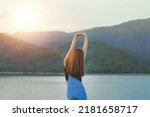 girl stretching her hands up with beautiful mountain and lake view as background in sunrise time