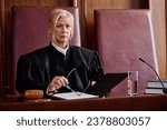 Small photo of Serious mature blond female judge of supreme court of justice in black mantle