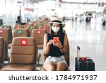 Airport terminal social distancing chair form corona virus pandemic. Young adult tourist woman sitting wear mask protect from covid 19. People travel with new normal lifestyle concept.