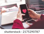 People youth culture dating online with application concept. Cloes up young woman hand using mobile phone with heart icon on device screen for meet up new love couple relationship.