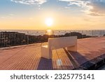 beautiful landscape with white stone bench on seafront embarkment during beautiful sunrise or sunset with sidewalk with pavement, sea surf and nice cloudy sunset sky