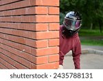 Small photo of Conspiracy using a motorcycle helmet - a guy is watching someone, looking out from behind the wall