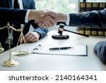 Small photo of Handshake after Lawyer providing legal consult business dispute service to the man at the office with justice scale and gavel hammer.