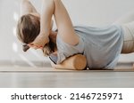 Small photo of Close up of woman rolling back on a cork massage roller to release tension in back muscles. Concept: self care practices at home, sustainable props, physical health