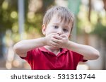 Small photo of Serious little Caucasian boy closing his mouth with hands. Illustrative image for childhood trauma, child traumatic experience. Psychological assistance, children rescue. Silent cry for help. Stutter